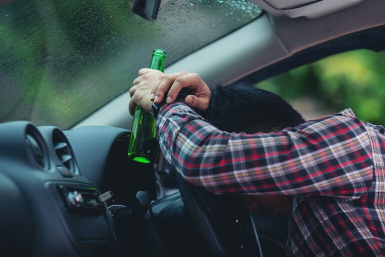 man holding a beer bottle while driving