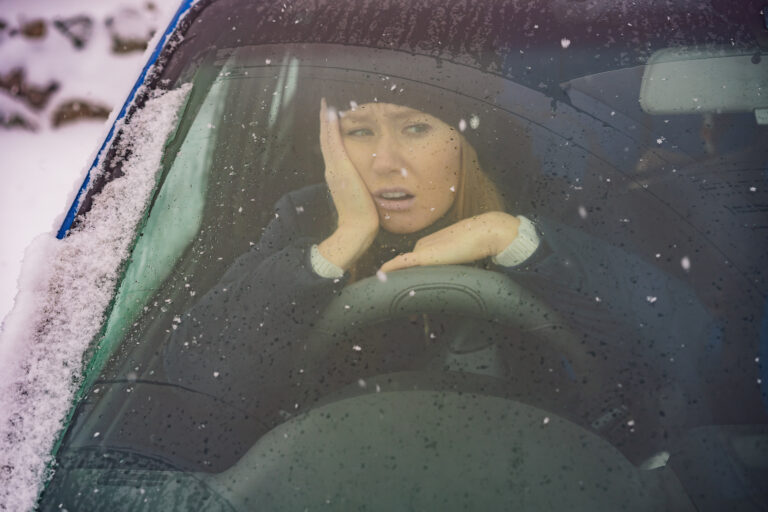 woman inside a car holding her face